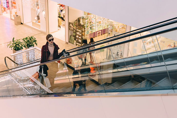 Stock photo of a woman with shopping bags, going up an escalator