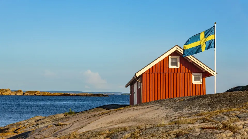 red house by the sea and a Swedish flagg