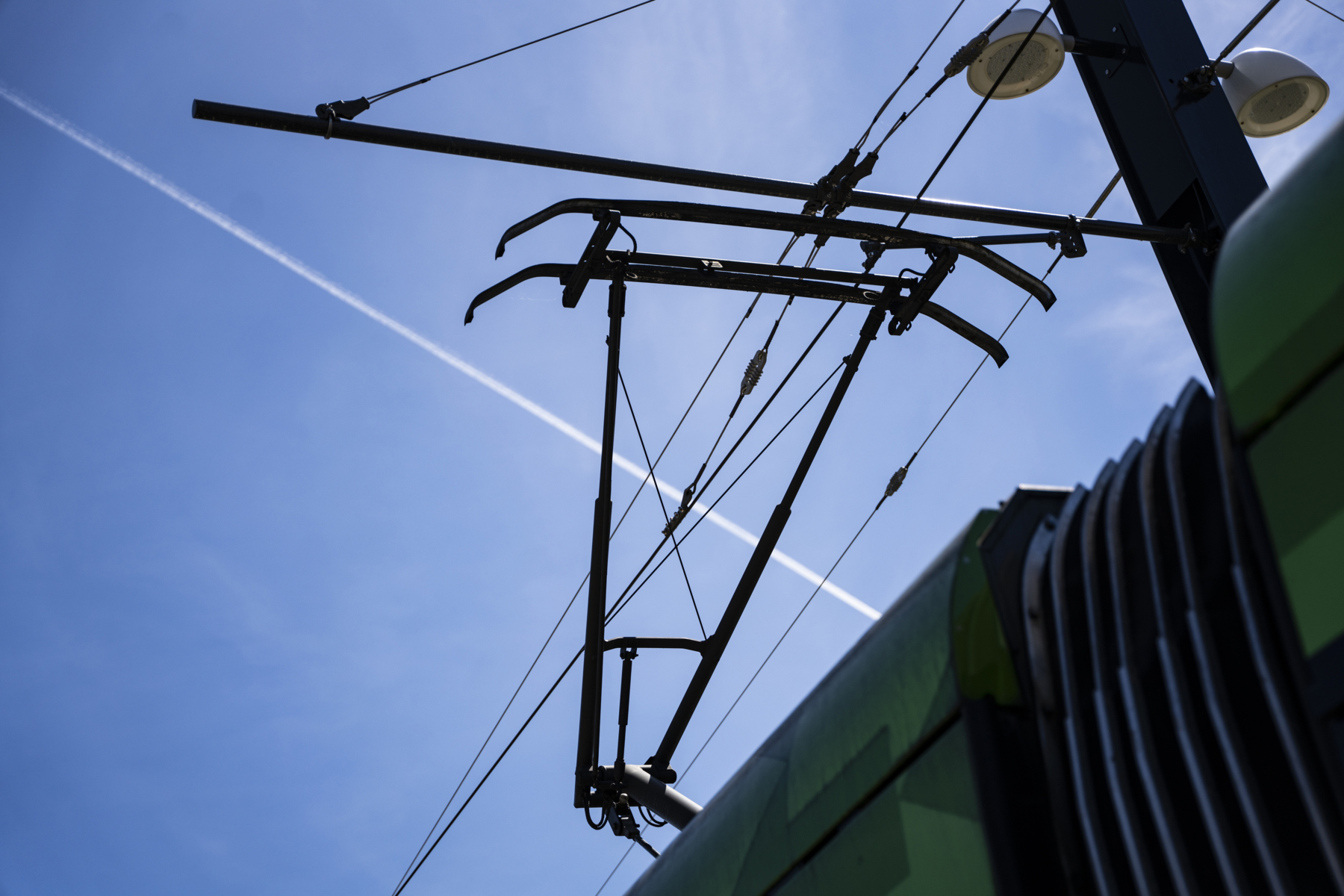 Photo of electric lines connected to a vehicle, like a tram or a train.