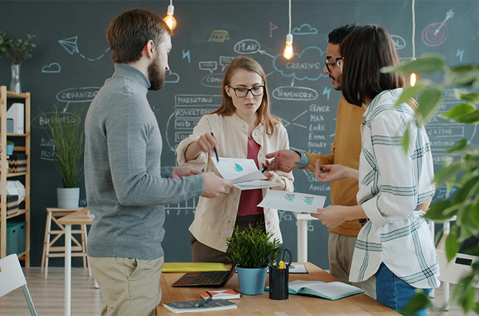 Stock photo of a people looking at a paper with diagrams, explained by a person in charge.
