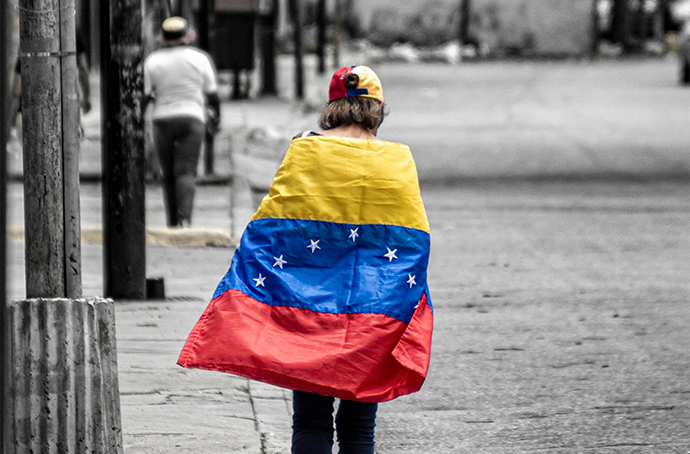 Stock photo of a person with a Venezuelan flag draped over their back.
