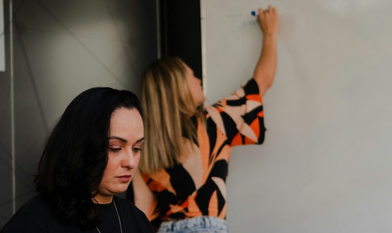 Två kvinnor, en skriver på whiteboard och en tittar ner